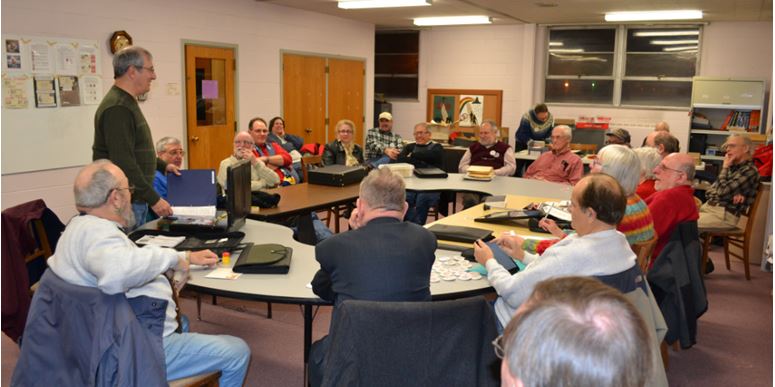 Club President Rich Spinelli (tanding) has everyone’s rapt attention at the Feb. 13th meeting.  The exhibits await to be judged on the board behind Rich.