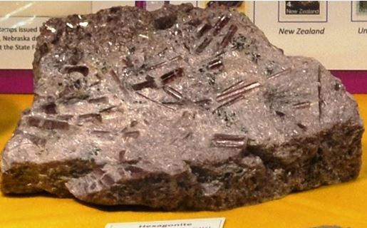 This 8” piece from Balmat displays several gemmy 1-2” long purple hexagonite crystals.